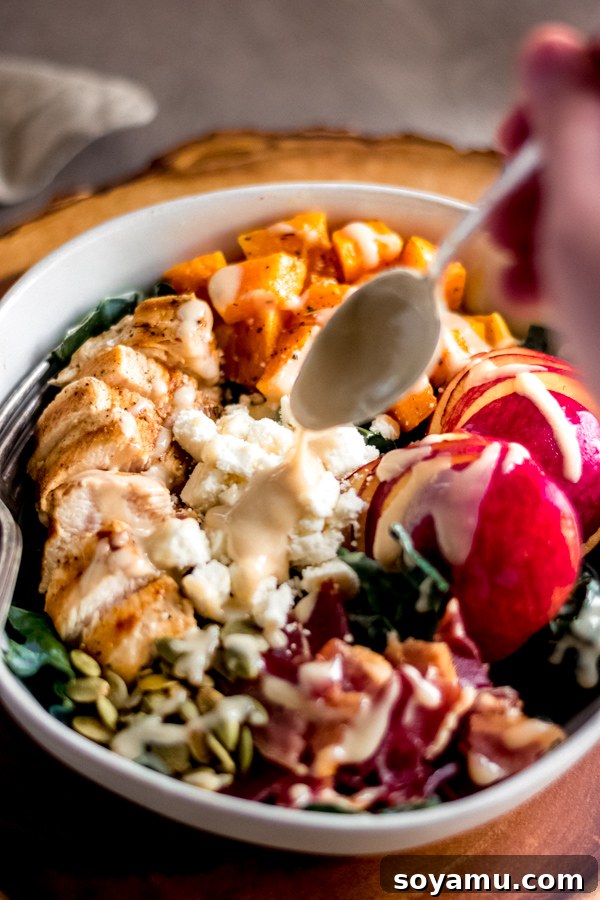 Fall Harvest Salad with Maple Tahini Dressing - A delicious salad filled with fall flavors and good-for-you ingredients like roasted butternut squash, honeycrisp apples, chicken, kale, and pumpkin seeds. No sad salads here! #butternutsquash #salad #fall #fallrecipes #mealprep #healthyrecipes #healthyfood #chicken #glutenfree | bluebowlrecipes.com A beautifully presented bowl of Fall Harvest Salad with Maple Tahini Dressing, ready to be enjoyed.