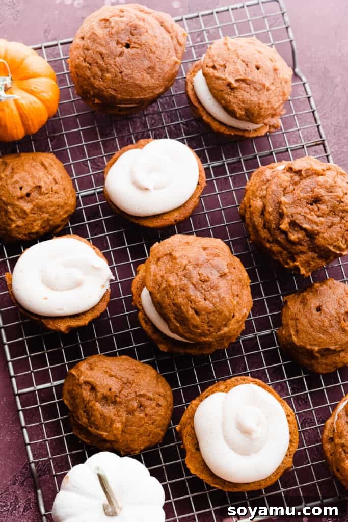 Brown Butter Pumpkin Whoopie Delights 8 Partially assembled whoopie pies on a cooling rack, showcasing the piping of the cream cheese filling.