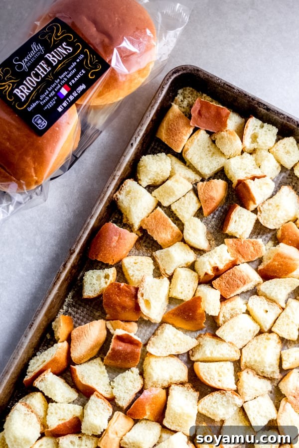 Cubed Brioche for Stuffing Fresh brioche buns, cubed and spread on a baking sheet, ready for toasting to dry out for perfect stuffing texture.