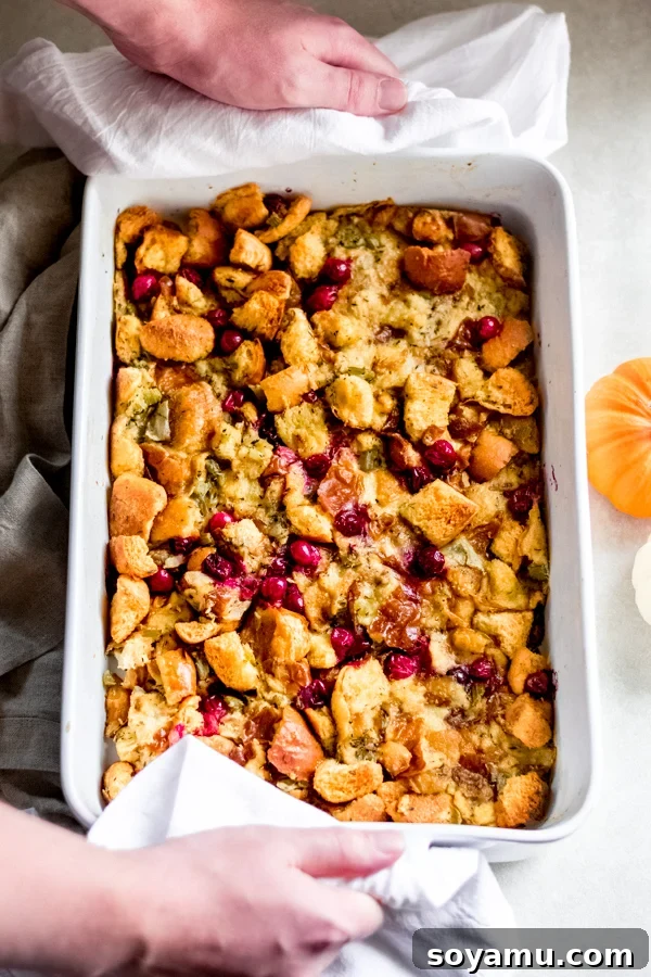 Baked Brioche Stuffing Crispy golden brioche stuffing with fresh cranberries, baked in a pan and garnished with herbs, ready to be served.