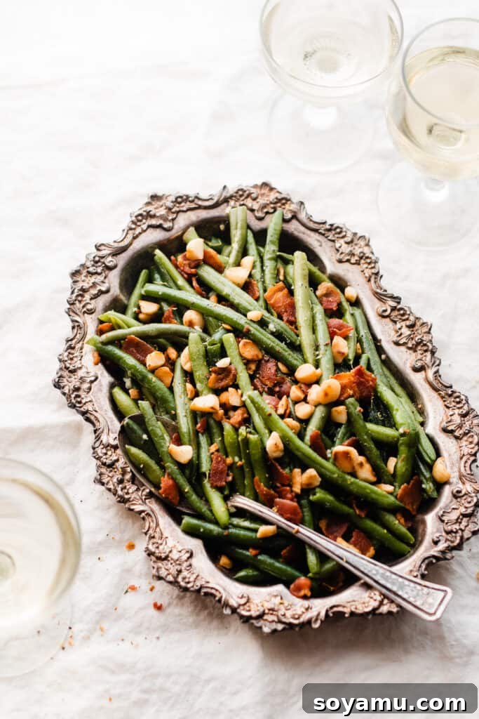 Effortless Gluten-Free Dairy-Free Bacon Green Beans 7 A serving spoon digging into a metal dish full of bacon green beans topped with toasted macadamia nuts.
