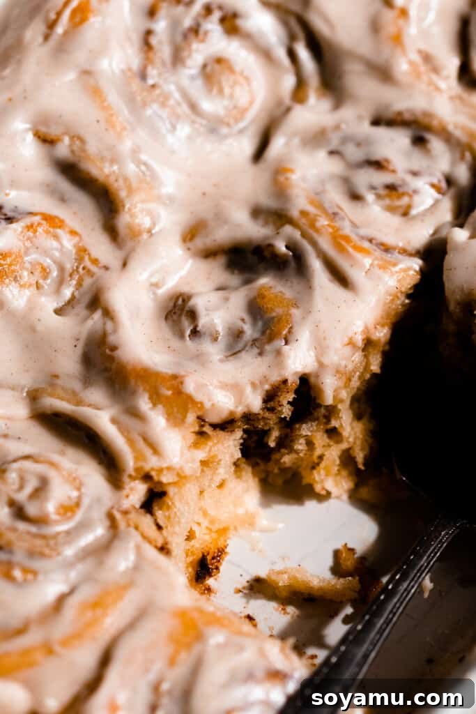 A close-up of the freshly iced brioche cinnamon rolls nestled together in the baking pan.