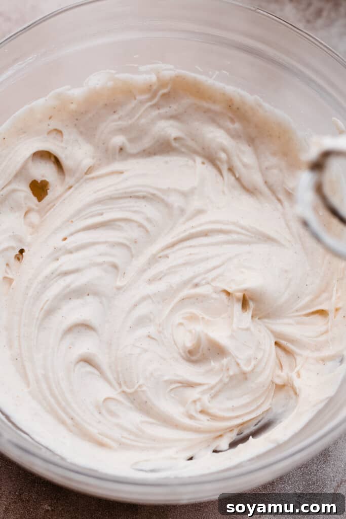 A bowl of rich and creamy maple cream cheese frosting, ready for the warm cinnamon rolls.