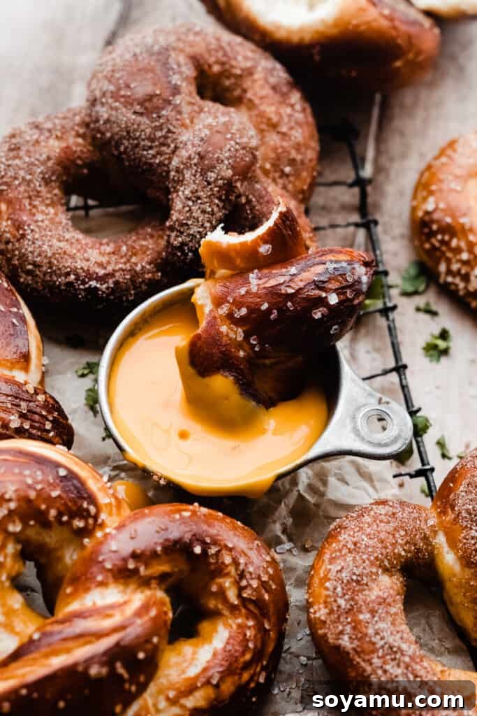 Homemade Soft Pretzel Trio 10 A delicious soft pretzel piece being dipped into a rich, creamy cheese sauce, ready to be enjoyed.
