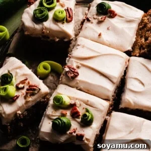 The sliced zucchini cake frosted and decorated with chopped nuts & zucchini spirals.
