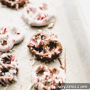 Mint Chocolate Pretzel Crunch 3 Chocolate dipped pretzels covered in crushed peppermint on a wax paper lined baking sheet, ready for setting.