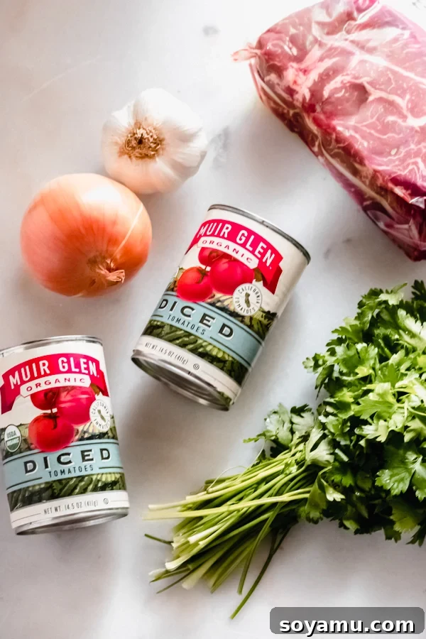 Ingredients for Braised Beef with Tomatoes + Gnocchi - showcasing fresh and organic produce. The wholesome ingredients laid out on a white surface, including beef chuck roast, canned tomatoes, and fresh aromatics.