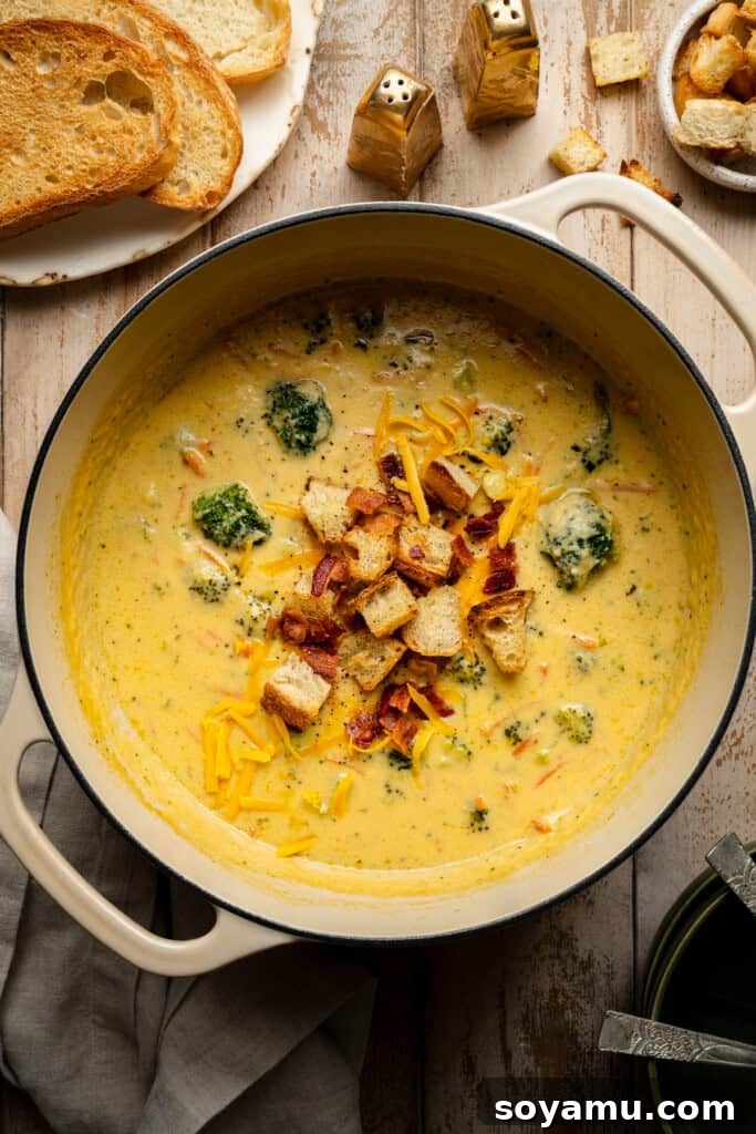A large Dutch oven filled with bubbling, golden broccoli cheddar soup, ready to be served.