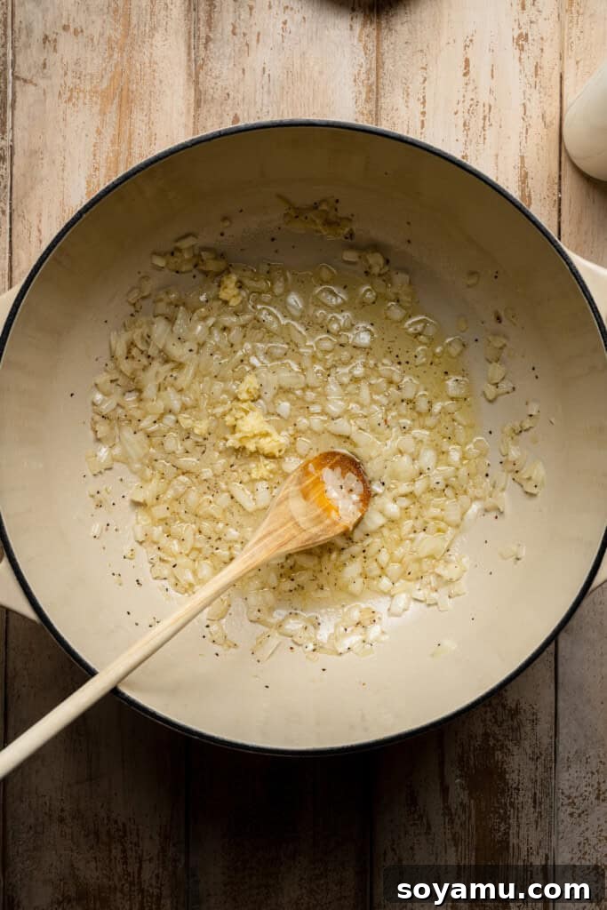 Onions and garlic being sautéed in a dutch oven, creating an aromatic base for the soup.