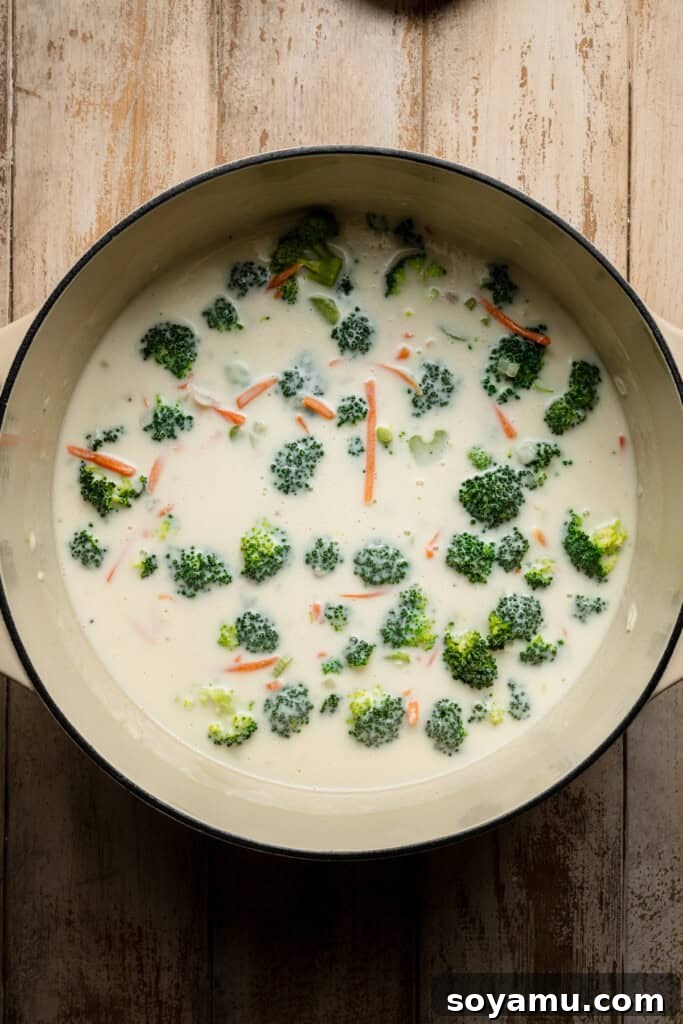 Vibrant broccoli florets and shredded carrots simmering in the rich, creamy soup base until tender.