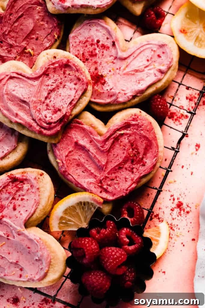 Bright pink frosted raspberry cookies on a wire rack. 