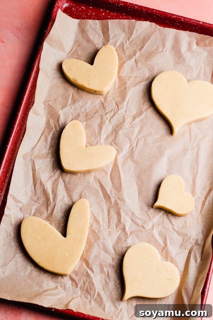 Heart cutout cookie shapes on a baking sheet before being baked. 