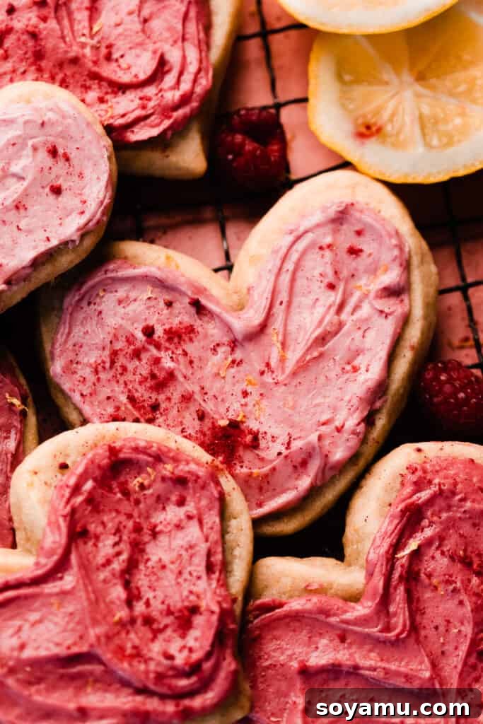 A close-up of a light pink heart cookie nestled among other cookies.