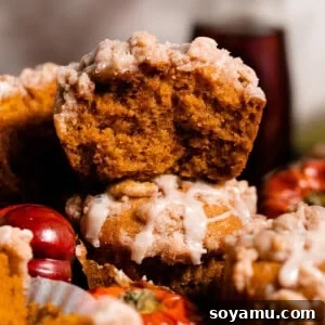 Maple-Drizzled Pumpkin Crumble Muffins 15 A close-up on a stack of muffins with one broken open, showing the fluffy moist insides.