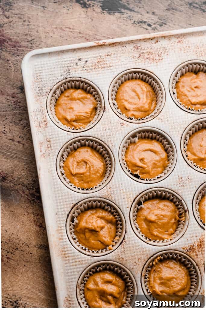 Maple-Drizzled Pumpkin Crumble Muffins 7 A muffin pan with paper liners filled with batter.