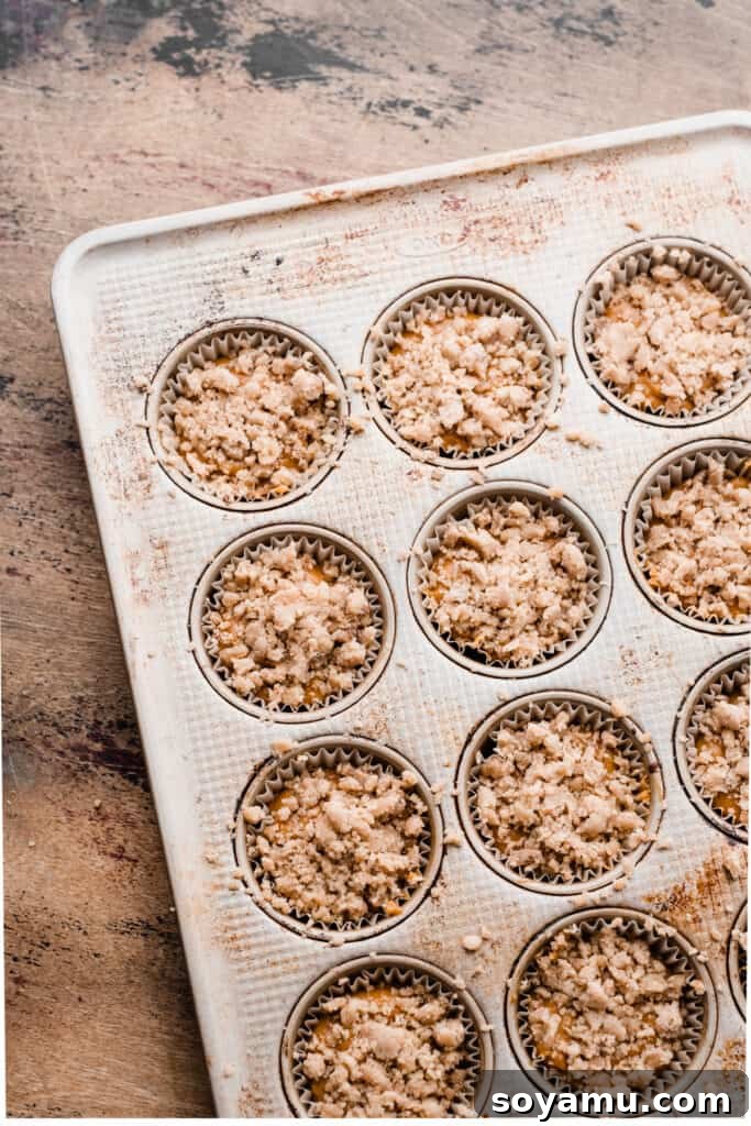 Maple-Drizzled Pumpkin Crumble Muffins 8 Muffin batter topped with streusel in the pan.