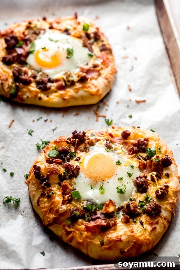 Perfectly baked breakfast pizzas with set eggs and melted cheese, ready to be enjoyed. A baking tray filled with golden-brown, freshly baked breakfast pizzas, hot out of the oven.