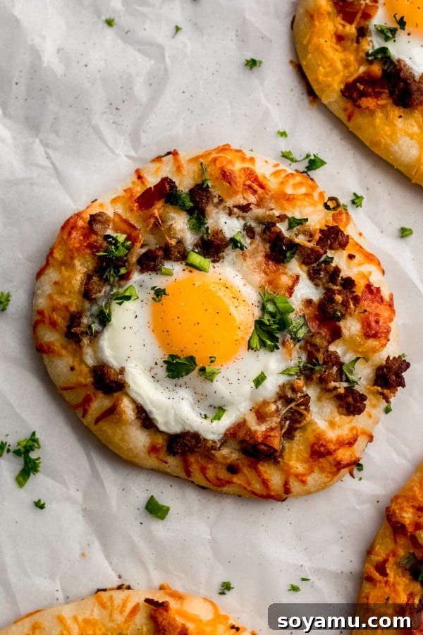 An enticing close-up of a breakfast pizza, highlighting its savory toppings. A close-up view of a single breakfast pizza, showing a perfectly cooked egg with a runny yolk, surrounded by melted cheese and bacon.