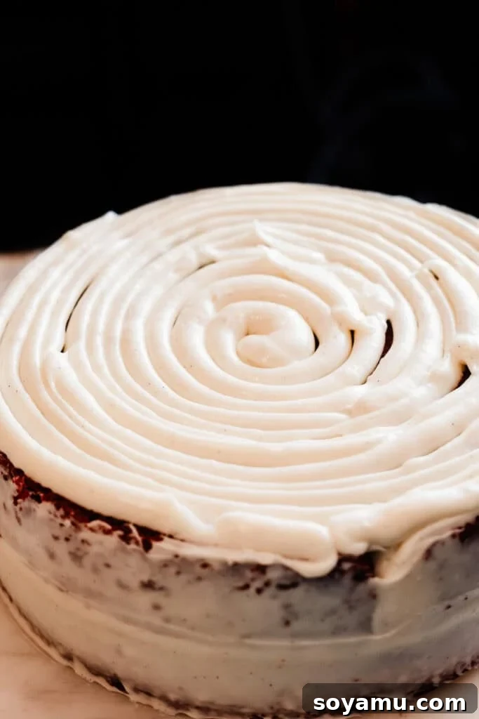 Decadent Red Velvet Dream 11 The top of the red velvet cake covered in a large spiral of cream cheese frosting, demonstrating even application for consistent layers.
