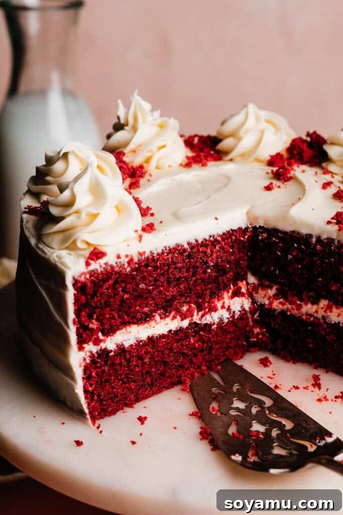 Decadent Red Velvet Dream 3 A close-up on the inside of a sliced red velvet cake, showing three perfectly baked layers and generous, silky cream cheese frosting.