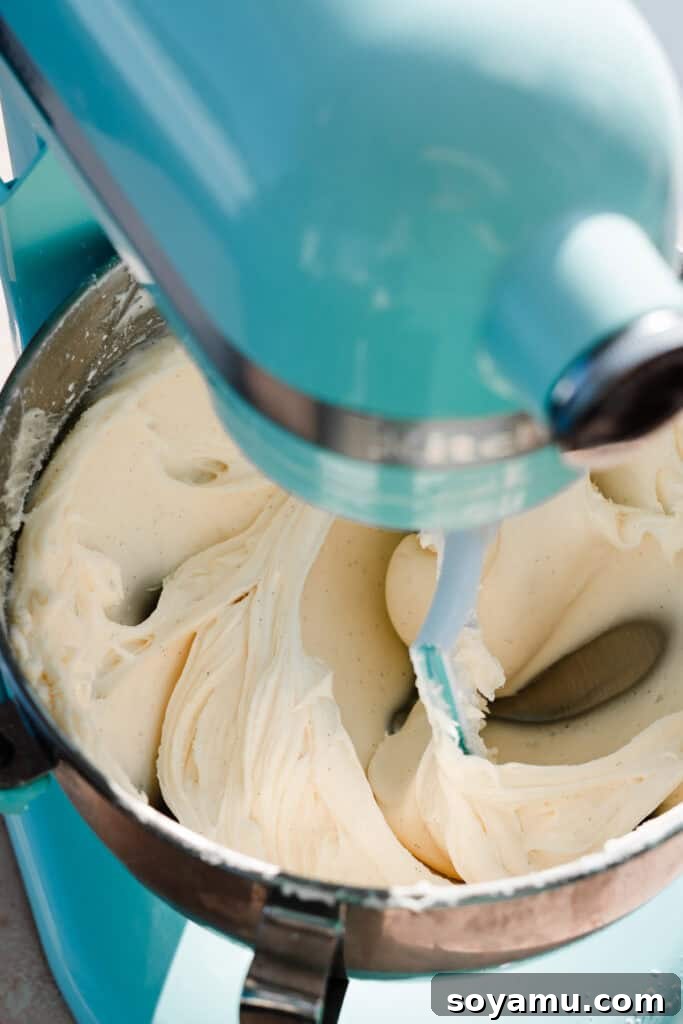 Silky Cream Cheese Frosting Perfection 2 A stand mixer full of silky cream cheese frosting, showcasing its smooth and fluffy texture, ready to be spread on delicious baked goods.
