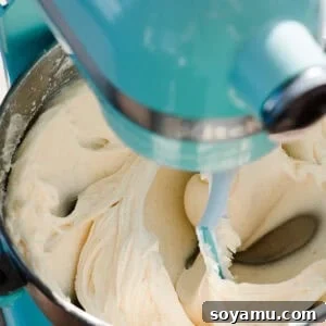 The bowl of a stand mixer filled with luscious cream cheese frosting, perfectly smooth and ready to be used for decorating.
