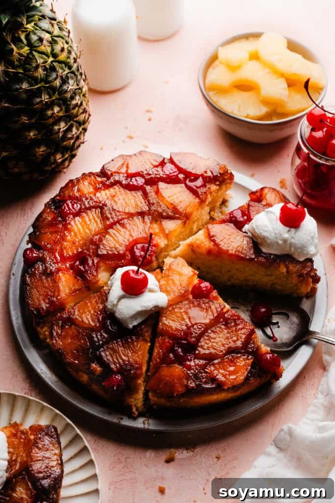 Caramelized Pineapple Dream 2 The pineapple upside down cake sliced, on a cake plate. A few of the slices have dollops of whipped cream and a maraschino cherry on top.