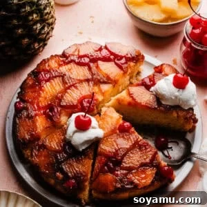 The sliced pineapple upside down cake on a cake plate. Slices are topped with dollops of whipped cream and maraschino cherries.