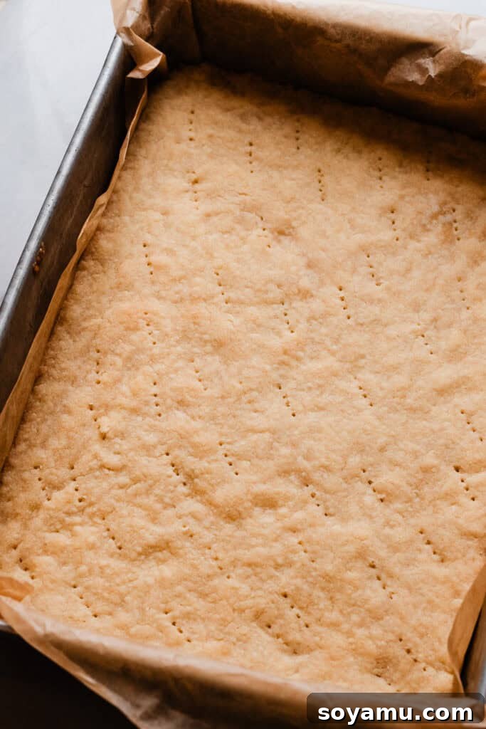 Effortless Zesty Lemon Bars 6 A pan of the freshly baked shortbread crust, pricked uniformly across its surface with a fork, preventing it from puffing during the second bake.