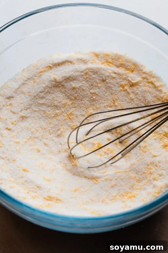 Effortless Zesty Lemon Bars 7 A bowl showing lemon zest rubbed into granulated sugar and combined with flour, forming a fragrant, sandy mixture.