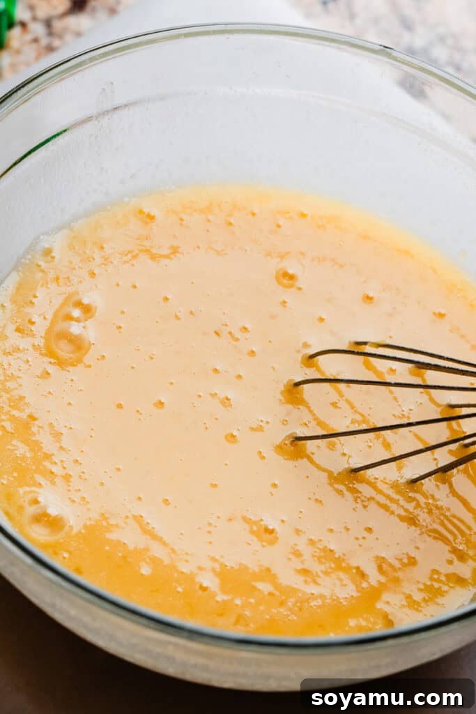 Effortless Zesty Lemon Bars 8 A smooth, pale yellow lemon filling mixture in a bowl, perfectly whisked and ready to be poured.