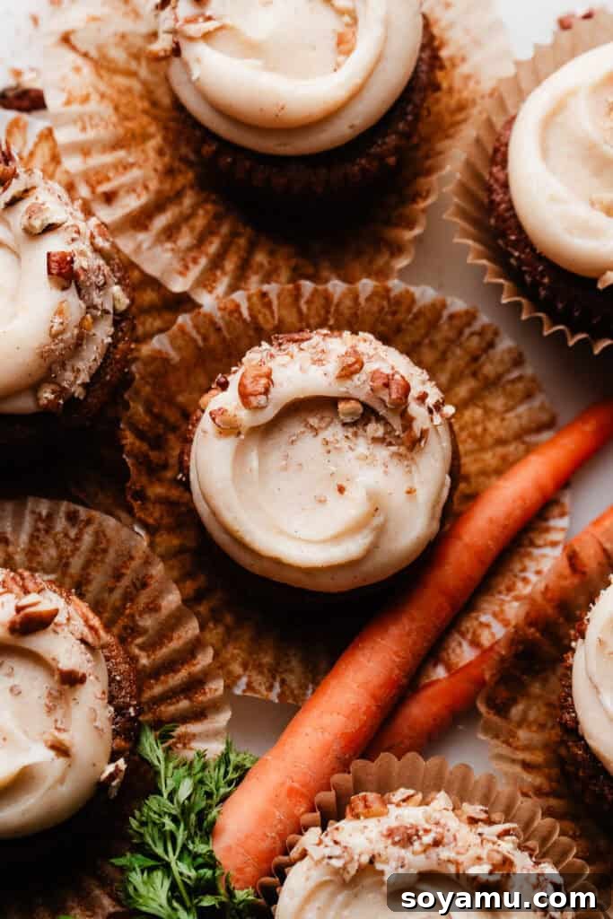 Brown Butter Cream Cheese Frosted Carrot Cupcakes 2 A stunning bird's eye view of several frosted carrot cake cupcakes, beautifully arranged with elegant frosting swirls and a sprinkle of crushed pecans on top.