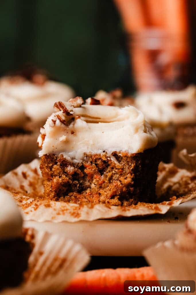 Brown Butter Cream Cheese Frosted Carrot Cupcakes 3 A close-up shot of a carrot cake cupcake with a bite taken out, revealing its wonderfully moist and tender interior texture, topped with creamy frosting.