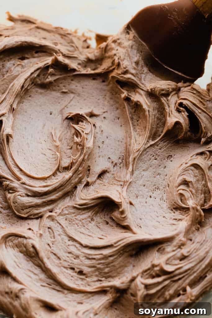Velvety Nutella Frosting 5 A close-up shot of rich, chocolatey Nutella frosting swirling beautifully in a mixing bowl, showcasing its creamy texture.