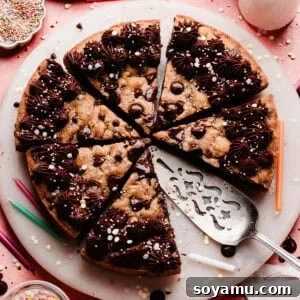 Chocolate Chip Cookie Cake Recipe — Soft, Chewy, Crowd-Pleasing 12 A photo of the sliced chocolate chip cookie cake on a marble plate. It's decorated with chocolate fudge frosting and sprinkles.