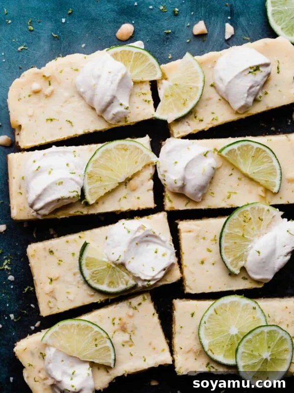Key Lime Pie Bars on a blue background with dollops of whipped cream & lime slices.
