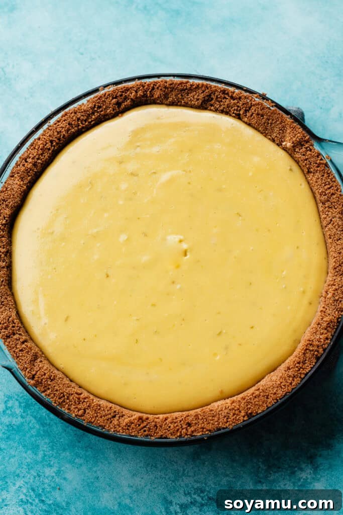 Ultra-Creamy Key Lime Pie Recipe for Perfectly Tangy Slices 11 The baked key lime pie resting on a blue surface. The pie has a slightly raised look on the surface that will disappear as it cools.