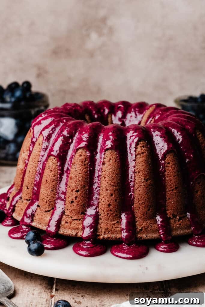 Double Blueberry Bundt Cake Recipe for Moist, Fruity Treat 13 The baked blueberry bundt cake, topped with a vibrant blueberry glaze, on a cake plate.