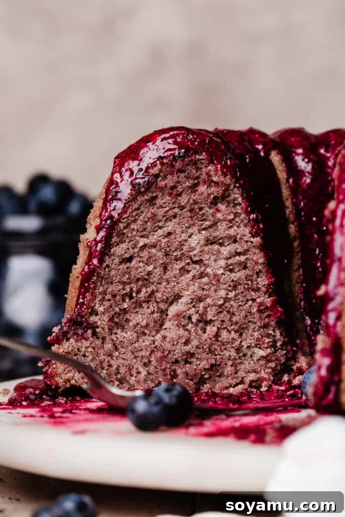 Double Blueberry Bundt Cake Recipe for Moist, Fruity Treat 14 A close-up on the inside of the sliced cake, topped with a vibrant blueberry glaze.