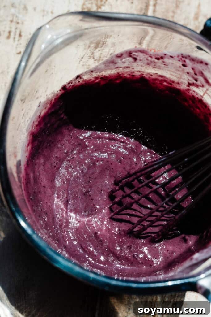 Double Blueberry Bundt Cake Recipe for Moist, Fruity Treat 9 A glass measuring cup full of the vibrant purple blueberry milk mixture.