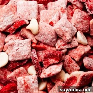 4-Ingredient Strawberries and Cream Puppy Chow Recipe 12 A close-up on the pink strawberry puppy chow pieces, mixed with freeze-dried strawberry pieces and white chocolate chips.