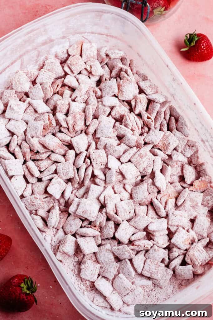 4-Ingredient Strawberries and Cream Puppy Chow Recipe 9 The coated strawberry chex in a tupperware container.