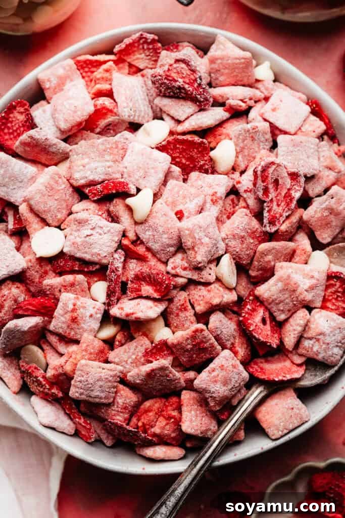 4-Ingredient Strawberries and Cream Puppy Chow Recipe 10 A close-up of a bowl of the strawberry chex, with a spoon digging in.