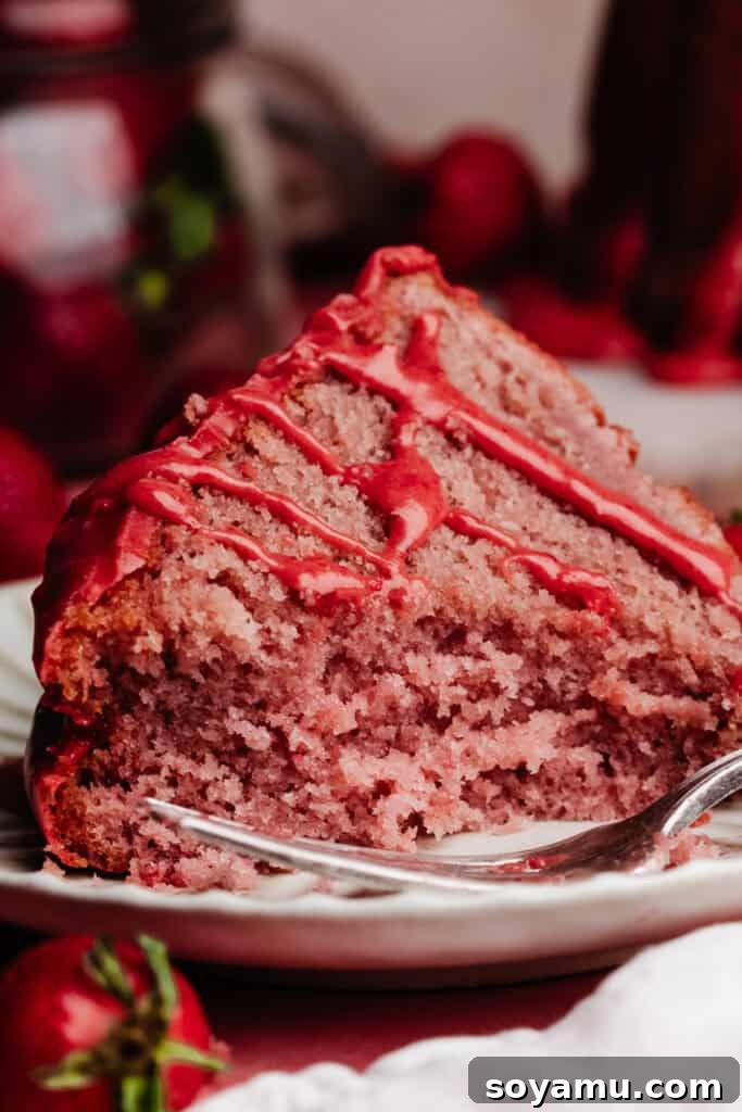 A close-up of a slice of strawberry bundt cake with a bite missing, showing the fluffy texture.