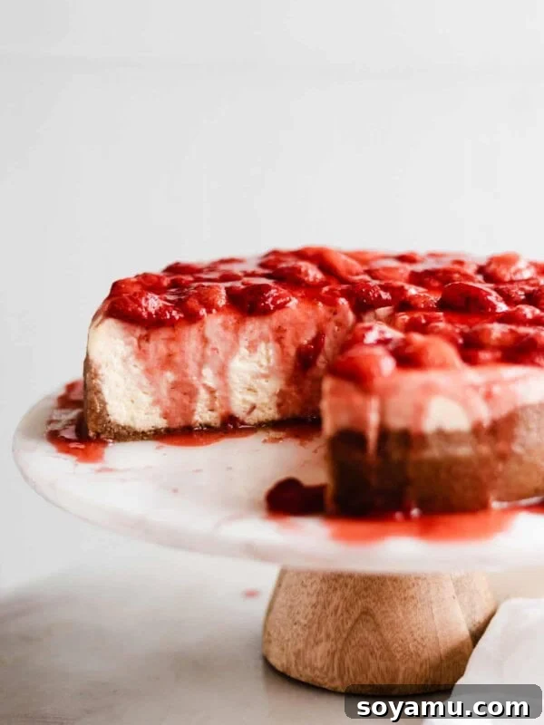 Sliced cheesecake on a cake stand with strawberry topping.