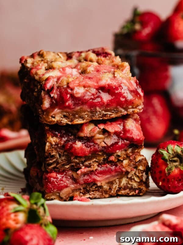 A stack of three strawberry oat crumble bars on a dessert plate.