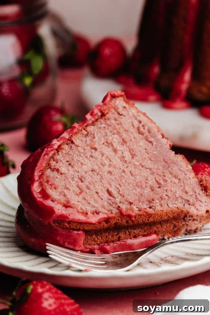 A slice of the strawberry bundt cake on a cake plate.