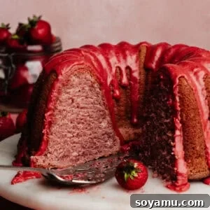 The sliced strawberry bundt cake on a cake plate, showing the fluffy texture inside and the vibrant pink glaze on top.