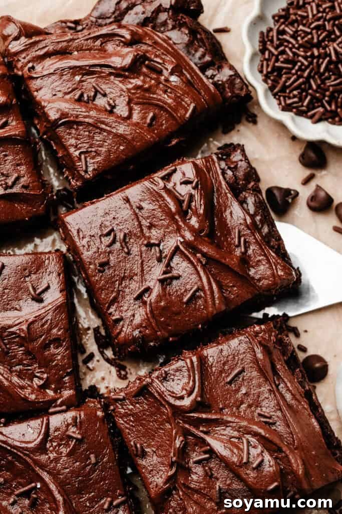 Sheet-Pan Brownies with Rich Chocolate Fudge Frosting 2 A close-up on the sliced, frosted brownies, with a spatula lifting one brownie away from the rest.