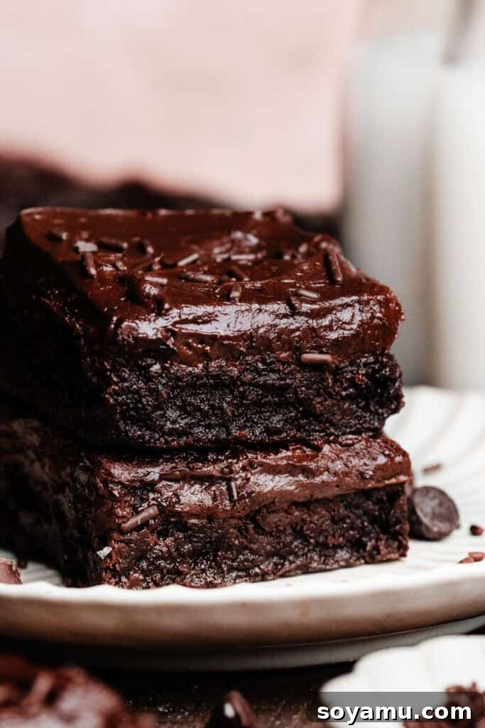 Sheet-Pan Brownies with Rich Chocolate Fudge Frosting 14 A stack of two frosted brownies on a plate.